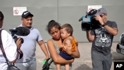 Adalicia Montecino and her husband Rolando Bueso Castillo are surrounded by the media as they walk with their year-old son Johan Bueso Montecinos, who became a poster child for the U.S. policy of separating immigrants and their children, in San Pedro.