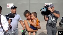 Adalicia Montecino and her husband Rolando Bueso Castillo are surrounded by the media as they walk with their year-old son Johan Bueso Montecinos, who became a poster child for the U.S. policy of separating immigrants and their children, in San Pedro Sula, Honduras, Friday, 20, 2018.
