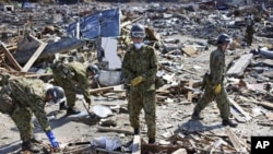 Japan Ground Self-Defense Force members sift through the rubble in the area devastated by the March 11 tsunami and earthquake in the town of Yamamoto, Fukushima Prefecture, Japan, April 24, 2011
