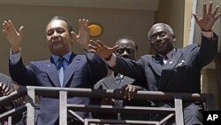 Dikteta wa zamani wa Haiti Jean-Claude 'Baby Doc' Duvalier, kushoto, awapungia mkono wafuasi wake kutoka baraza ya chumba cha hotel, Port-au-Prince, baada ya kurudinyumbani kutoka uhamishoni 2011. 