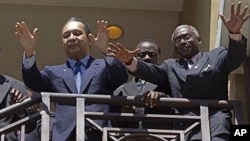 Haiti's former dictator Jean-Claude 'Baby Doc' Duvalier, left, greets supporters from the balcony of his hotel room in Port-au-Prince, 19 Jan. 2011