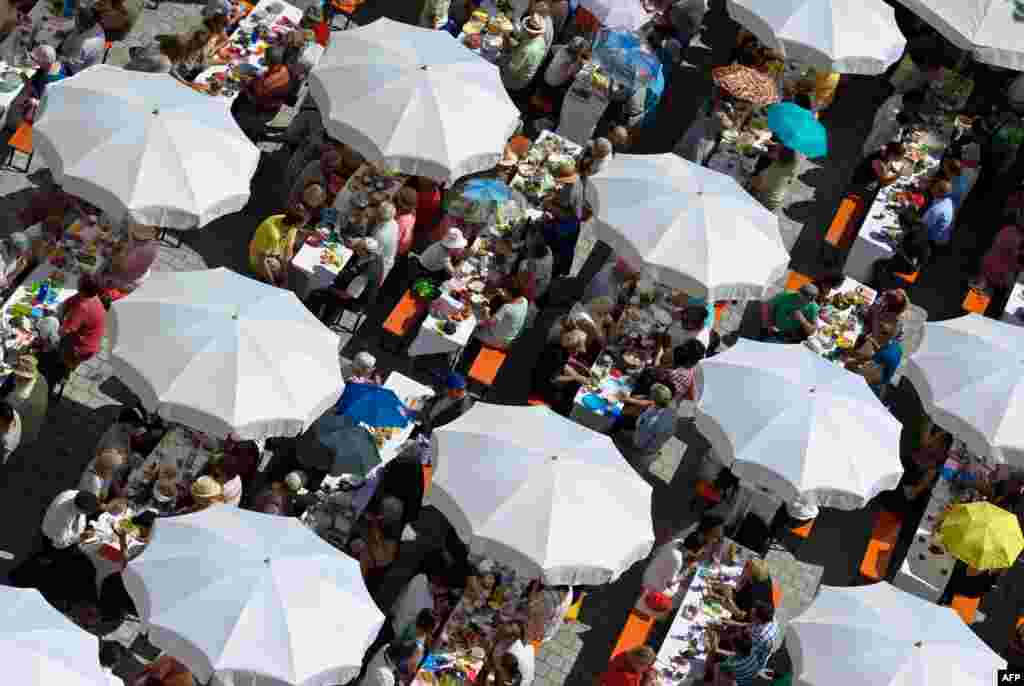 People share a meal under umbrellas at the Augsburg Peace Festival in Augsburg, southern Germany. The festival is celebrated every year on August 8 and is a public holiday.