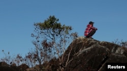 A man sits on a rock at the border between Venezuela and Brazil in Pacaraima, Roraima state, Brazil, Feb. 23, 2019. 