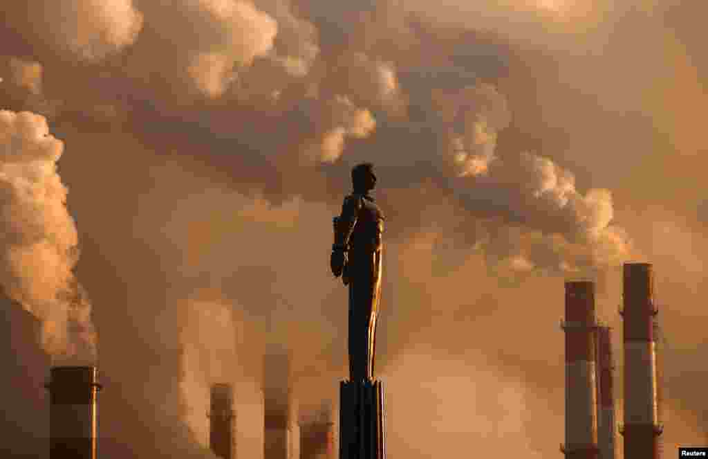 Sovet kosmonavtı Yuri Qaqarinin heykəlinin arxa fonunda elektrik stansiyasının trubalarından tüstü qalxır. Moskva, Rusiya.