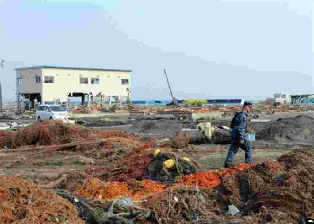 In a March 14, 2011 photo provided by the Navy Visual News Service, U.S. Navy Mineman 2nd Class Cody Stone of Phoenix, Az., walks through debris during a cleanup effort at the Misawa Fishing Port in Misawa, Japan. More than 90 sailors from Naval Air Facil