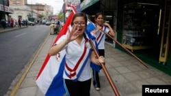 Paraguayan schoolgirls carry flags as they wear sashes a day before the inauguration of President-elect Fernando Lugo's government in Asuncion August 14, 2008.