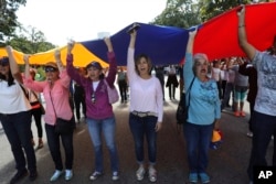 Members of the opposition hold up a Venezuelan flag and sing their national anthem before handing out explainers to soldiers and police about an amnesty law, near Fort Tiuna military base in Caracas, Venezuela, Jan. 27, 2019.