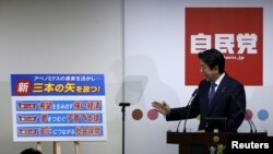 Japan's Prime Minister Shinzo Abe explains his three new arrows of 'Abenomics' policy, during a news conference after he was reelected as the party leader at the party headquarters in Tokyo, Sept. 24, 2015. 