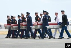 Miembros de diferentes ramas militares trasladan cajas de transferencia de un C-17 a una ceremonia en la Base Conjunta Pearl Harbor-Hickam en Hawai, que marca la llegada de los restos que se cree que pertenecían a soldados estadounidenses que cayeron en la Guerra de Corea. Miércoles 1 de agosto de 2018.