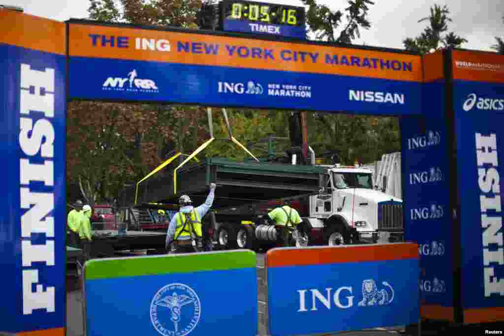 Workers install a platform after the ceremonial painting of the New York City Marathon blue line at Central Park, New York, Oct. 30, 2013. 