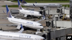 United Airlines planes are parked at their gates as another plane, top, taxis past them at George Bush Intercontinental Airport in Houston, July 8, 2015.