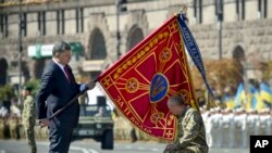 Ukrayna Prezidenti Petro Poroşenko hərbi bölmənin bayrağını əsgərə təqdim edir.