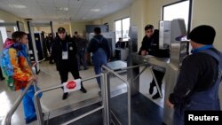 Security guards check visitors at the entrance to the olympic park in Adler near Sochi, Jan. 16, 2014. 