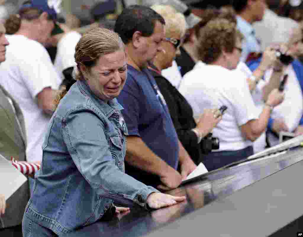 A woman cries while looking at the names inscribed at the North Pool of the 9/11 Memorial during tenth anniversary ceremonies at the World Trade Center site in New York, September 11, 2011.