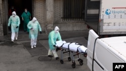 A health worker carries a body on a stretcher outside Gregorio Maranon hospital in Madrid on March 25, 2020.