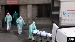 A health worker carries a body on a stretcher outside Gregorio Maranon hospital in Madrid on March 25, 2020.