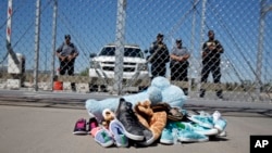 FILE- Shoes and a teddy bear, brought by a group of U.S. mayors, are piled up outside a holding facility for immigrant children in Tornillo, Texas, near the Mexican border, June 21, 2018.