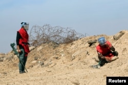 FILE - A demining team works near the village of Bitr, in Shalamjah district, east of Basra, Iraq, March 4, 2018. Taiwan announced Monday it was contributing $1 million to support demining operations in Iraq and Syria.
