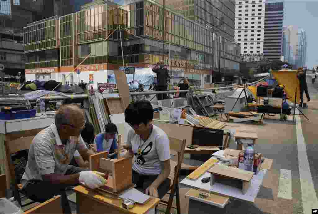 Para demonstran pro-demokrasi membuat kursi kecil di daerah yang diduduki di luar kantor-kantor pusat pemerintahan di distrik Admiralty, Hong Kong (27/10).&nbsp;(AP/Vincent Yu) 