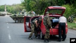 Ukrainian police and paratroopers check a car as they and other comrades block a road outside the town of Slovyansk, Ukraine, on May 4, 2014.
