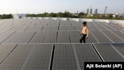 An Indian security man walks amid rooftop solar plant at the secretariat gymkhana in Gandhinagar, India, Tuesday, May 17, 2016.