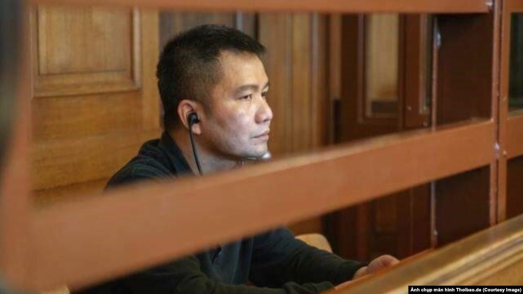 Bị cáo Nguyễn Hải Long ngồi trong phòng kính chống đạn tại tòa Thượng thẩm Berlin. (Ảnh chụp màn hình Thoibao.de)