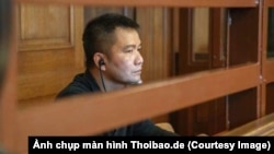 Bị cáo Nguyễn Hải Long ngồi trong phòng kính chống đạn tại tòa Thượng thẩm Berlin. (Ảnh chụp màn hình Thoibao.de)