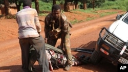 In this Sept. 16, 2013 photo, a Gabonese soldier from a regional Central African peacekeeping force helps collect the bodies of rebels who were reportedly killed by armed villagers in Njoh, Central African Republic.
