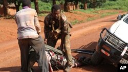 In this Monday, Sept. 16, 2013 photo, A Gabonese soldier from a regional Central African peacekeeping force helps collect the bodies of rebels who were reportedly killed by armed villagers in Njoh, Central African Republic.