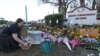 Suzanne Devine Clark, una profesora de arte en la escuela primaria Deerfield Beach, coloca piedras pintadas en un memorial frente a la escuela secundaria Marjory Stoneman Douglas en el primer aniversario del mortal tiroteo el jueves, 14 de febrero de 2019 en Parkland, Florida.