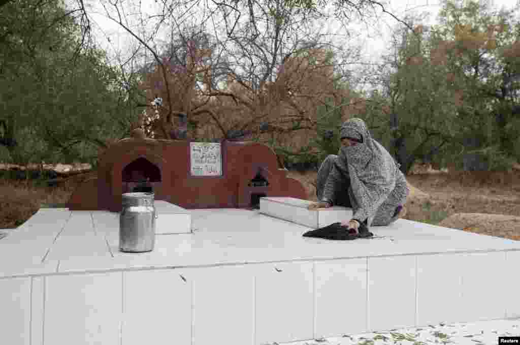 ہندو برادری سے تعلق رکھنے والی 20 سالہ نیحا اپنے خاندان کے بزرگ کی قبر کو صاف کر رہی ہے۔