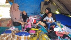 Seorang ibu menidurkan anak balitanya di dalam tenda terpal di Posko Pengungsian Buah Hati, Kelurahan Karema, Kota Mamuju, Sulawesi Barat. Selasa (26/1/2021). (Foto: VOA/Yoanes Litha)