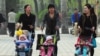 FILE - Women push babies in prams through a Beijing park during a public holiday, April 5, 2011.