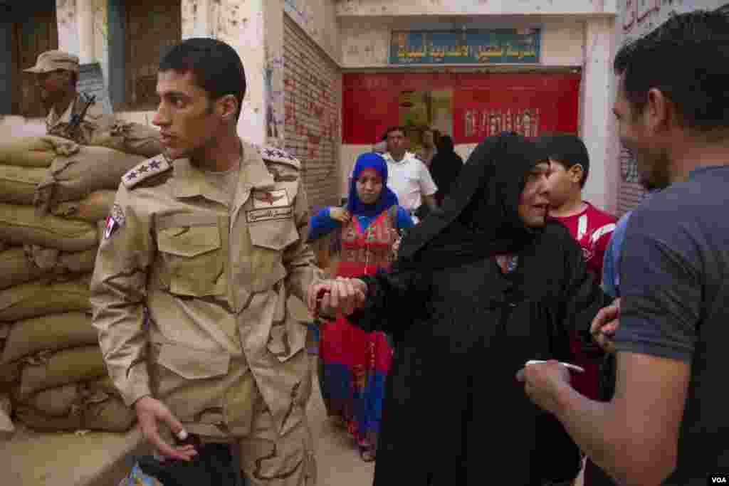 A soldier helps a woman at a polling station in Cairo, May 27, 2014. (Hamada Elrasam /VOA)