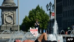 Người dân nằm tắm nắng gần một đài phun nước ở phố cổ Montreal