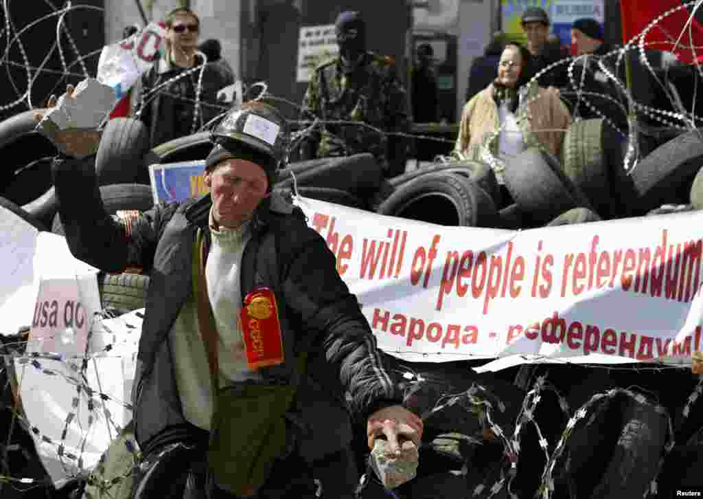 A pro-Russia protester breaks a piece of stone at a barricade outside a regional government building in Donetsk, in eastern Ukraine, April 15, 2014.