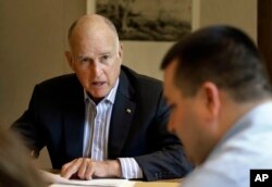 California Gov. Jerry Brown discusses a bill with budget analyst Chris Ferguson, right, in Sacramento, Calif., July 7, 2017.
