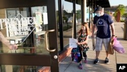 Paul Quisenberry drops his daughter Audra, 6, off at Premier Martial Arts on her first day of school Monday, Aug. 24, 2020, in Wildwood, Mo. (AP Photo/Jeff Roberson)