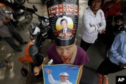 FILE - A supporter of the now dissolved opposition Cambodia National Rescue Party wears a poster of party leader Kem Sokha as she stands outside the Supreme Court in Phnom Penh, Cambodia, Oct. 31, 2017.
