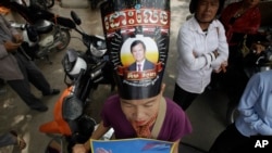 FILE - A supporter of the now dissolved opposition Cambodia National Rescue Party wears a poster of party leader Kem Sokha as she stands outside the Supreme Court in Phnom Penh, Cambodia, Oct. 31, 2017.
