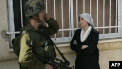 Một phụ nữ Palestine đứng cạnh một binh sĩ Israel trong một cuộc phản đối về việc Israel mở rộng khu lập cư