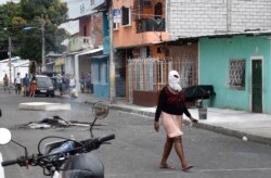 Una mujer camina con un pañuelo en la cabeza para evitar el olor del cadáver de una persona que presuntamente falleció de la COVID-19 en Guayaquil, Ecuador, el 3 de abril de 2020.
