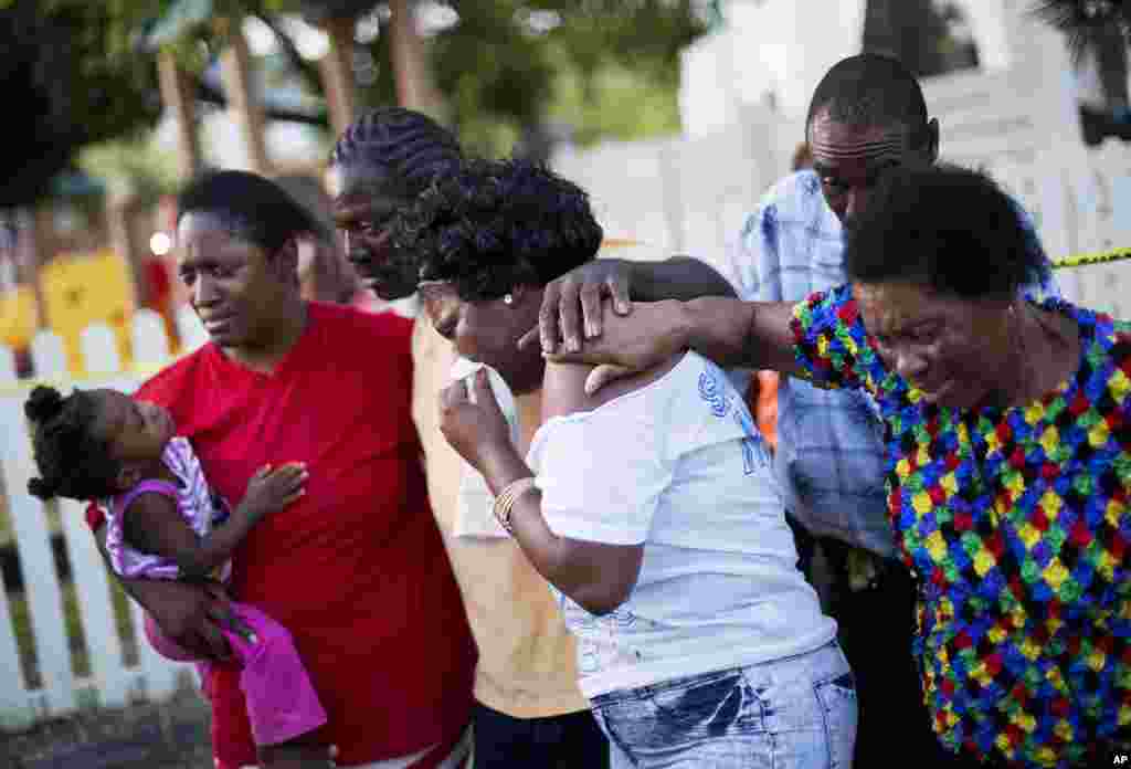 Gary and Aurelia Washington, center left and right, the son and granddaughter of Ethel Lance who died in Wednesday's shooting, leave a sidewalk memorial in front of Emanuel AME Church comforted by fellow family members, June 18, 2015, in Charleston, S.C.