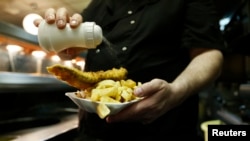 Manager Michael Upton adds salt to a customer's fish and chips at Mr Fish restaurant in north London May 22, 2012. Deep-fried fish in a crispy batter with fat golden chips is still as popular as ever with the British public, ranked alongside roast beef, Y