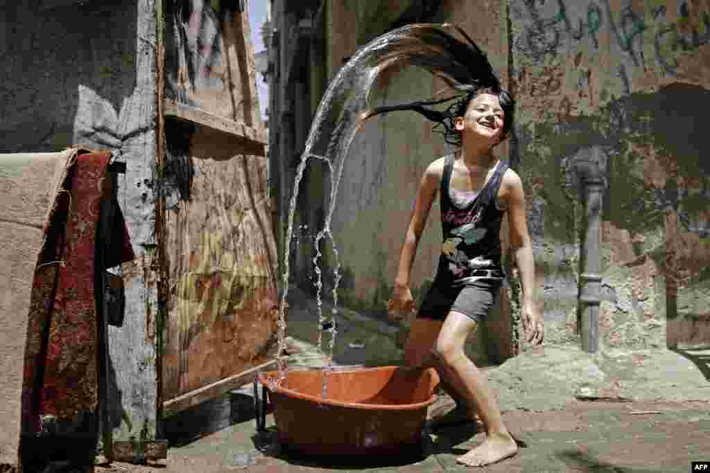 A Palestinian girl plays with water to cool off during a heatwave at Bureij refugee camp in the central Gaza Strip.