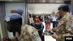 Anggota pasukan perdamaian PBB mengawal staf PBB dan keluarganya yang baru tiba di bandara Larnaca dari Kairo.