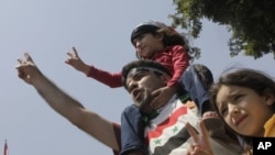 A Syrian family shouts anti-Syrian President Bashar Asssad slogans as they wear Syrian independence flags during anti-Syrian regime protest outside the Arab League headquarters in Cairo, Egypt, July 3, 2011