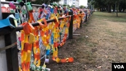 Paper links are draped over the fence at Hagley Park near one of the mosques were more than 40 people were killed in Christchurch, March 15, 2019. (S. Miller/VOA)