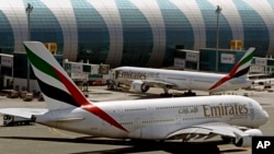FILE - This May 8, 2014 file photo shows Emirates passenger planes at Dubai airport in United Arab Emirates. The U.S. government is temporarily barring passengers on certain flights originating in eight other countries from bringing most types of electronics in their carry-on luggage. (AP Photo/Kamran Jebreili, File)