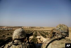 FILE - American troops look out toward the border with Turkey from a small outpost near the town of Manbij, northern Syria, Feb. 7, 2018.